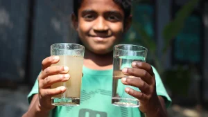 Child comparing a glass of dirty water and clean water