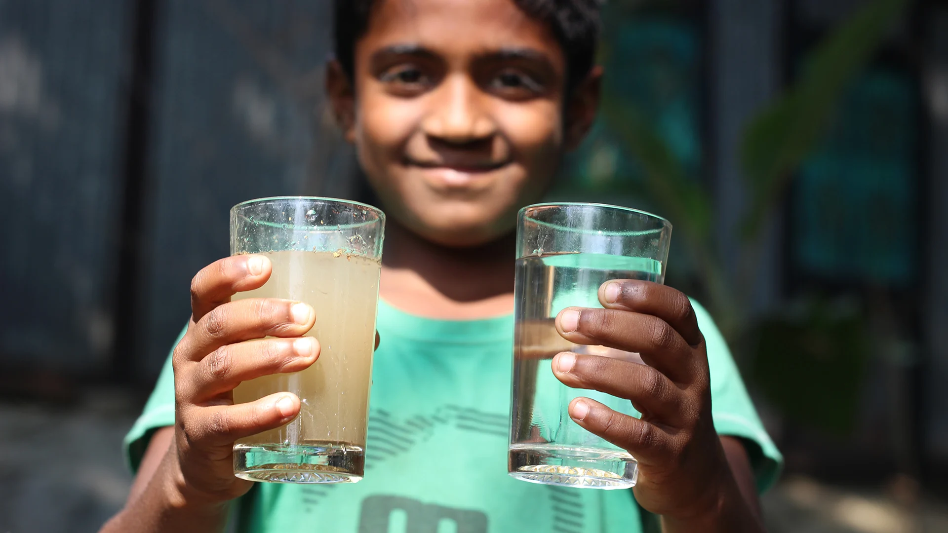 Child comparing a glass of dirty water and clean water