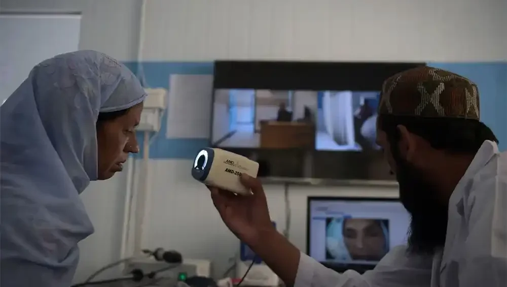 Man scanning woman’s face at computer desk and Healthcare in Rural Pakistan